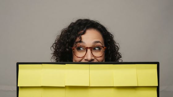 Creator peers over a monitor covered in sticky notes